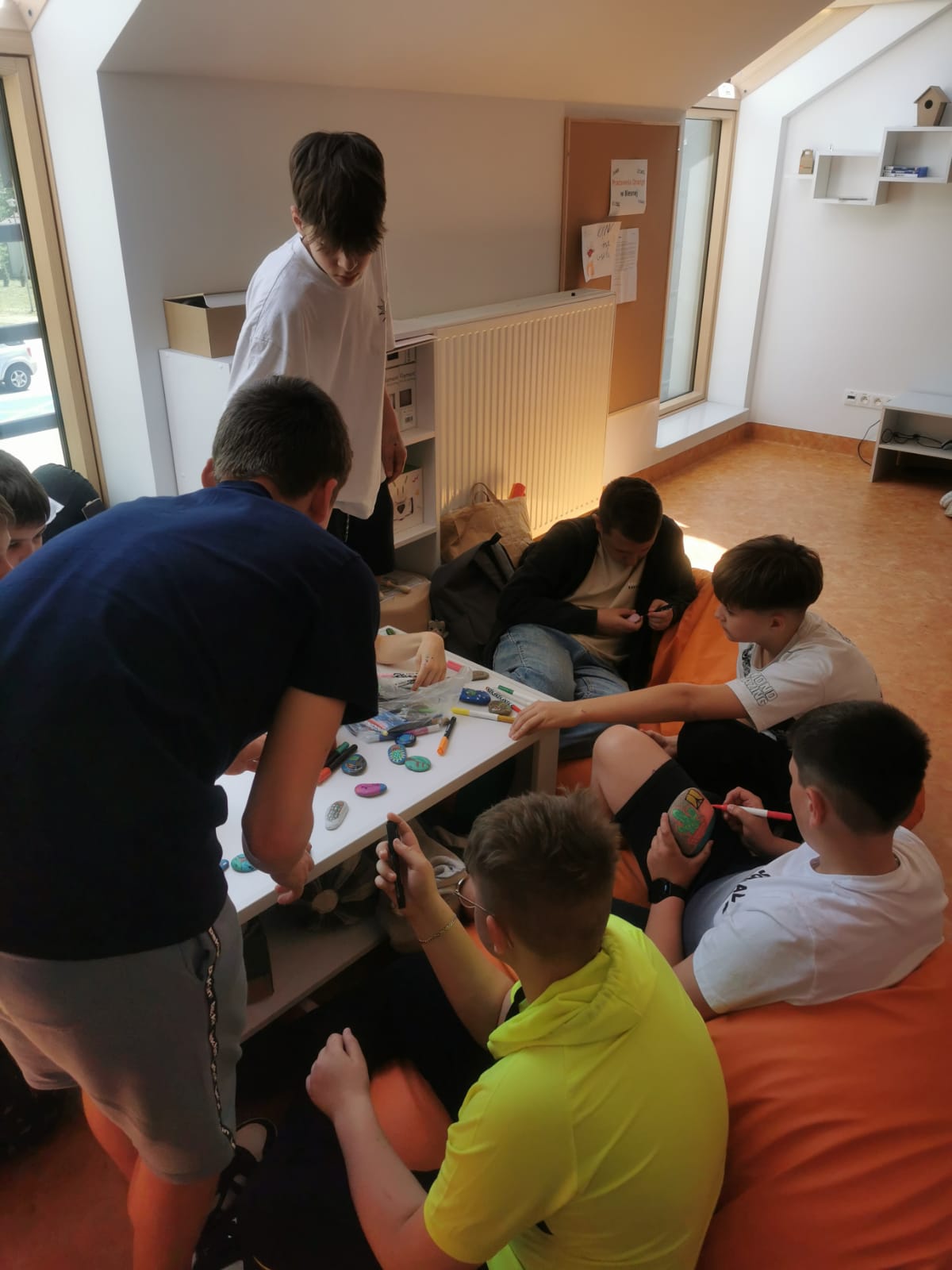 Grupa młodzieży w Pracowni Orange podczas malowania kamyczków.