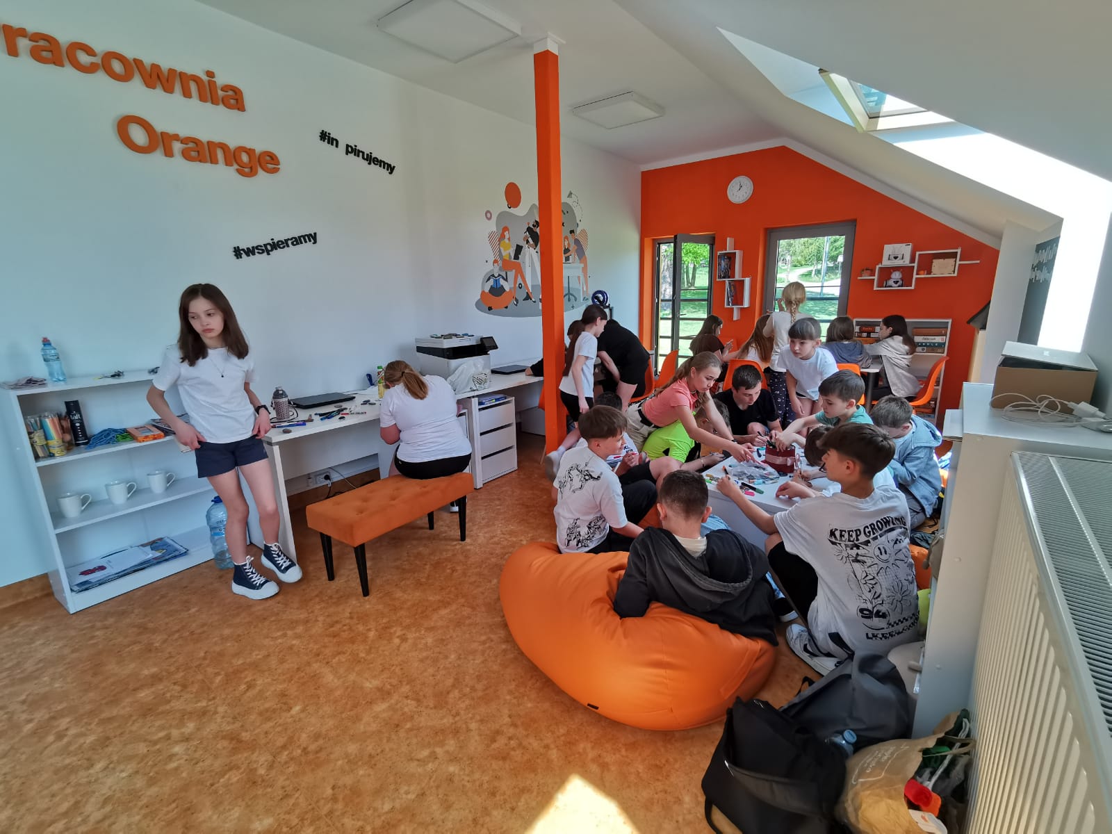 Kolorowe zdjęcie. Grupa młodzieży maluje kamienie w Pracowni Orange.