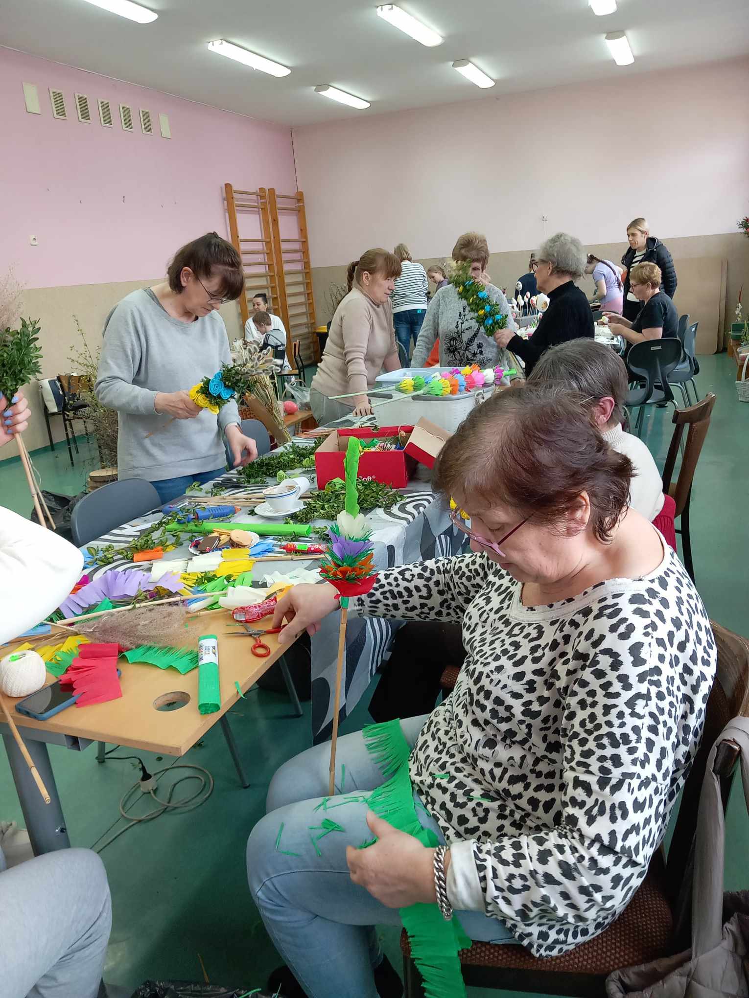 Grupa osób robiących palmy wielkanocne.