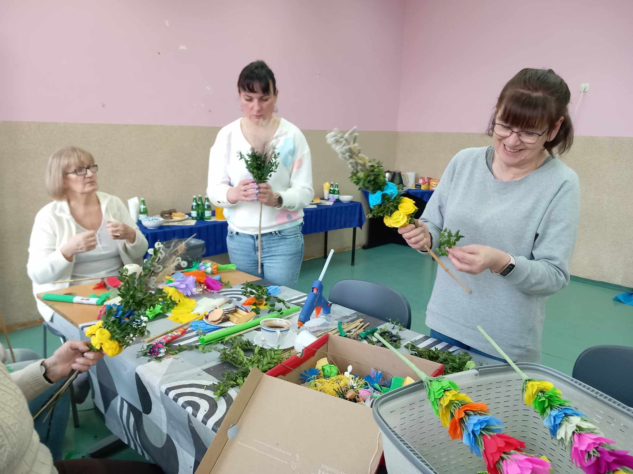 Trzy kobiety tworzące palmy wielkanocne.